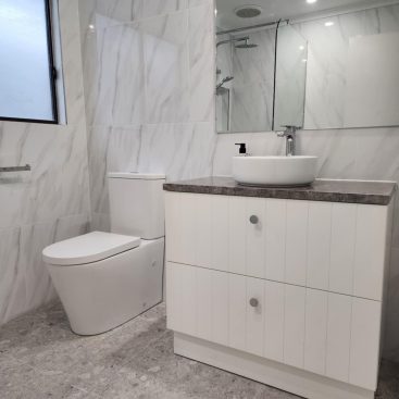 New white toilet and vanity in grey bathroom at Aldinga.