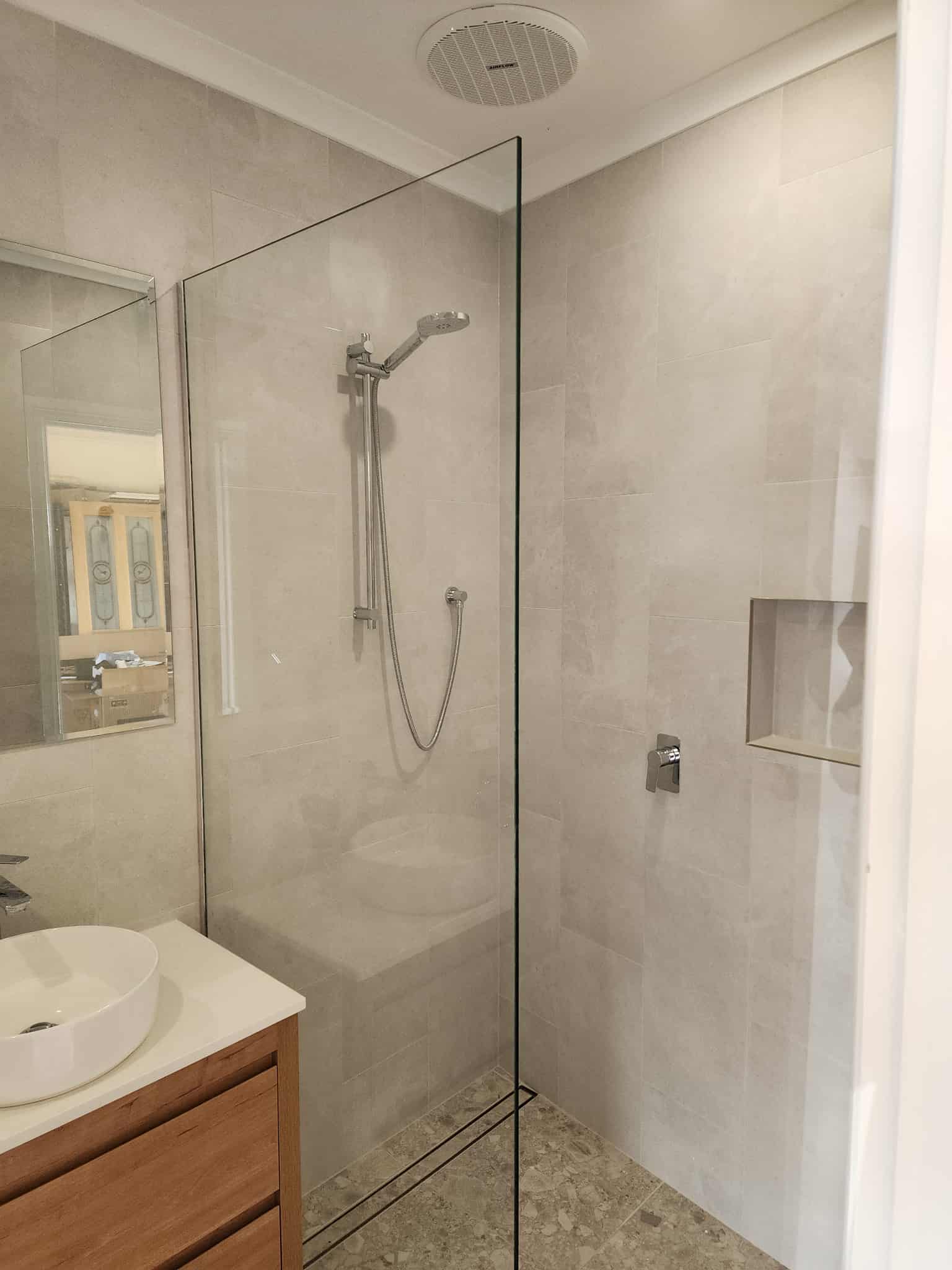 Garage conversion to a bathroom - Fleurieu renovation Glass shower screen, white vanity on wooden drawers in a garage converted to a bathroom.