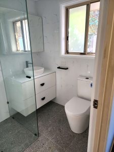Glass shower screens, floating white vanity and white toilet in a compact bathroom in Victor Harbor.